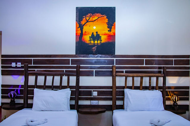 Twin beds beneath a hand-painted sunset canvas